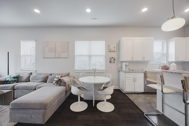 interior space with open floor plan, pendant lighting, white cabinetry, and light stone countertops