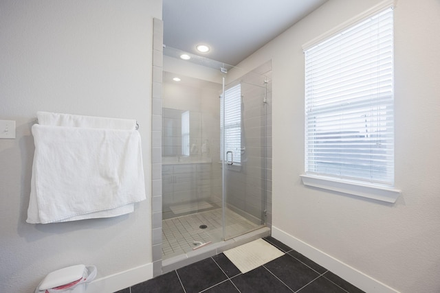 full bathroom featuring plenty of natural light, a shower stall, baseboards, and tile patterned floors