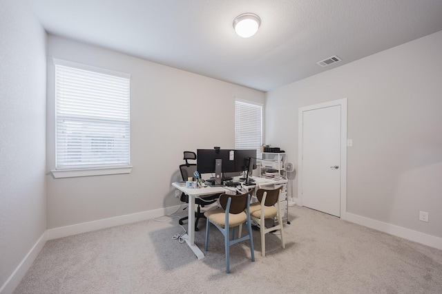 office area with baseboards, visible vents, and light colored carpet