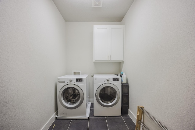 laundry room with dark tile patterned flooring, visible vents, baseboards, cabinet space, and washing machine and clothes dryer