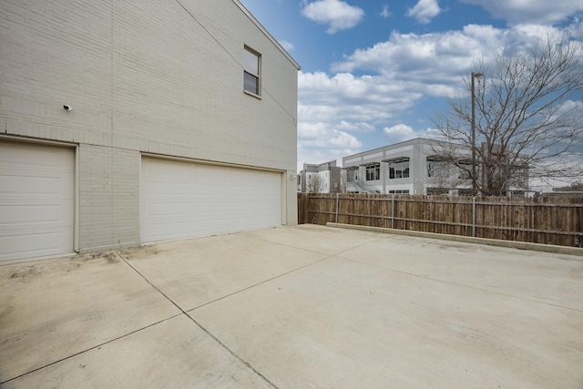 view of side of home with a garage, fence, and brick siding