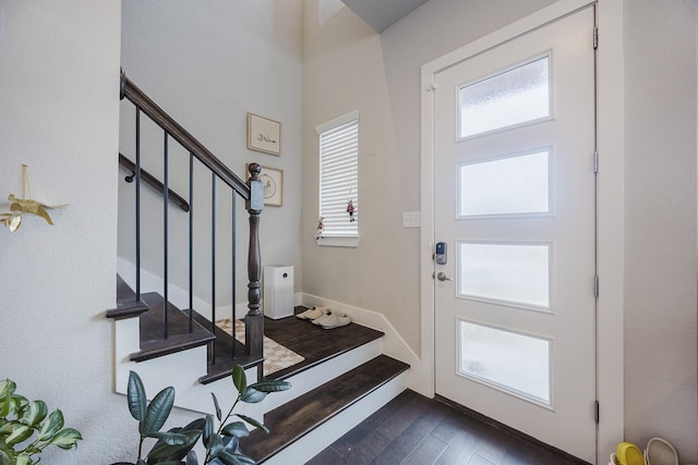 foyer entrance featuring stairs, dark wood-style flooring, and baseboards