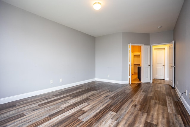 unfurnished bedroom with dark hardwood / wood-style floors and a spacious closet