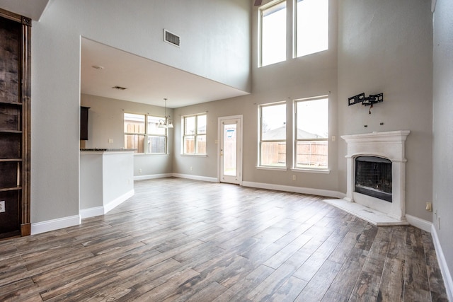 unfurnished living room featuring dark hardwood / wood-style floors, a chandelier, and a high ceiling