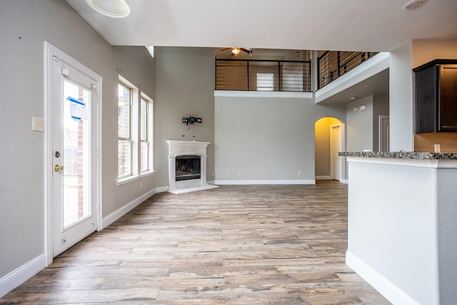 unfurnished living room with a towering ceiling and light wood-type flooring