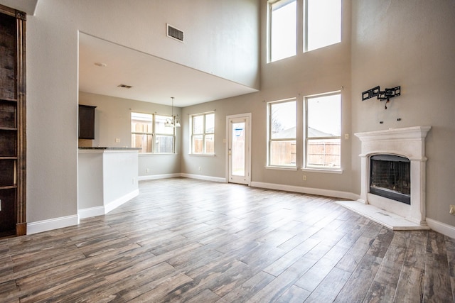 unfurnished living room with a notable chandelier, dark wood-type flooring, and a high ceiling