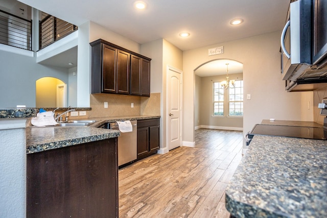 kitchen featuring sink, dark brown cabinets, light wood-type flooring, appliances with stainless steel finishes, and backsplash