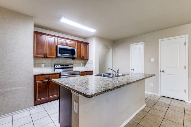 kitchen featuring sink, light tile patterned floors, stainless steel appliances, and a center island with sink