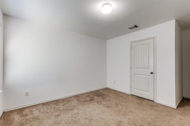 empty room featuring light carpet and a textured ceiling