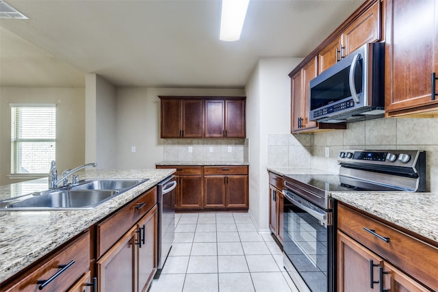 kitchen featuring light tile patterned flooring, sink, tasteful backsplash, appliances with stainless steel finishes, and light stone countertops