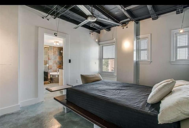 bedroom with multiple windows, concrete floors, and ensuite bath