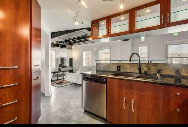 kitchen featuring stainless steel dishwasher, dark stone counters, track lighting, and sink