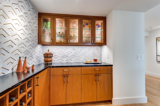 bar with tasteful backsplash and light hardwood / wood-style flooring