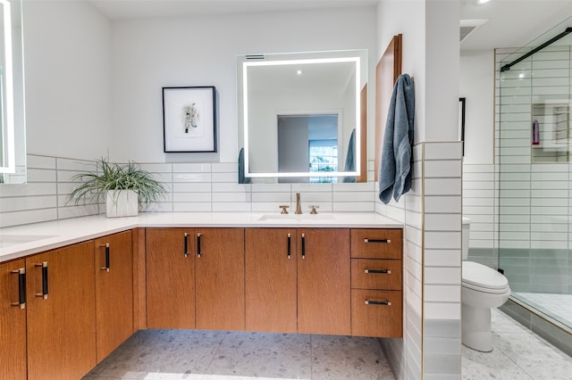 bathroom with tasteful backsplash, vanity, a shower with door, and toilet