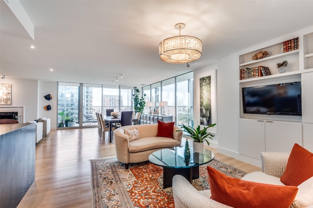 living room featuring built in features, floor to ceiling windows, a fireplace, and light hardwood / wood-style flooring