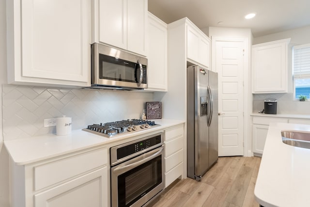 kitchen with white cabinetry, light hardwood / wood-style flooring, stainless steel appliances, and tasteful backsplash