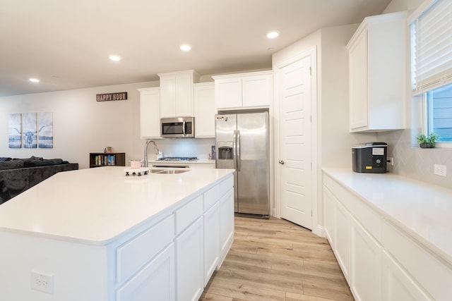 kitchen with tasteful backsplash, light hardwood / wood-style flooring, a center island with sink, stainless steel appliances, and white cabinets