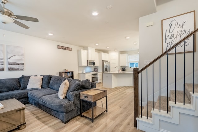 living room with ceiling fan, sink, and light hardwood / wood-style floors