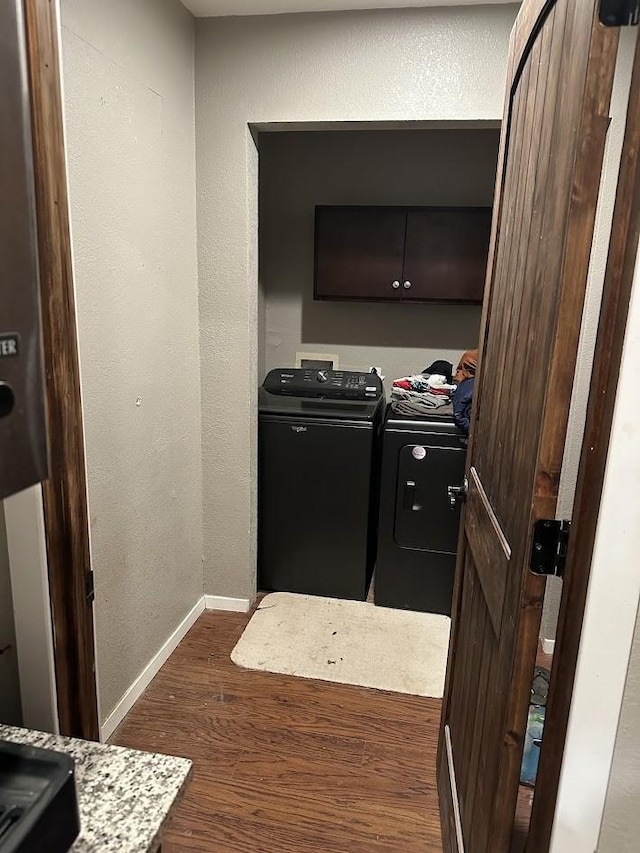 washroom featuring a textured wall, washer and clothes dryer, dark wood finished floors, and baseboards