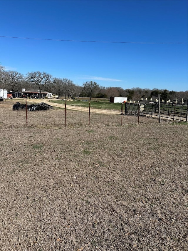 view of yard with fence and a rural view
