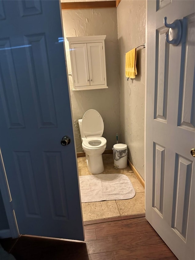 bathroom with baseboards, wood finished floors, and a textured wall