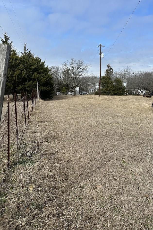 view of yard with fence and a rural view