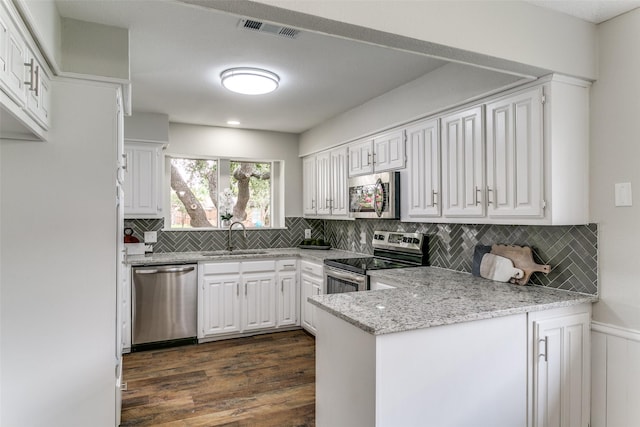2261 Woodcreek, Carrollton, TX 75006 - kitchen featuring appliances with stainless steel finishes, sink, white cabinets, light stone counters, and kitchen peninsula