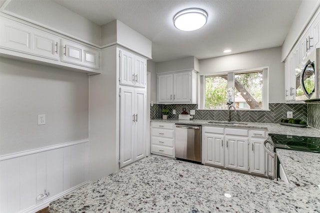 2261 Woodcreek, Carrollton, TX 75006 - kitchen with appliances with stainless steel finishes, tasteful backsplash, white cabinetry, sink, and light stone counters