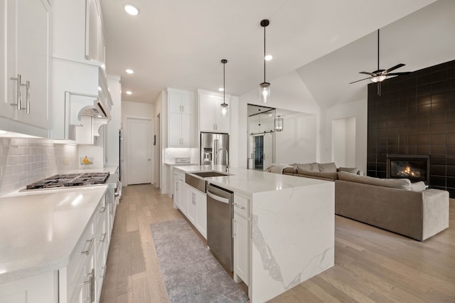 kitchen featuring sink, a center island with sink, white cabinets, and decorative light fixtures