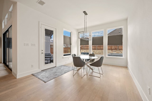 unfurnished dining area with an inviting chandelier, light hardwood / wood-style flooring, and a wealth of natural light