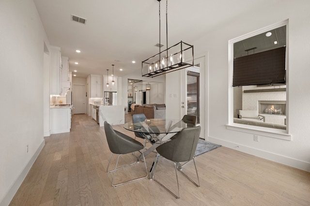 dining room with a fireplace and light hardwood / wood-style floors