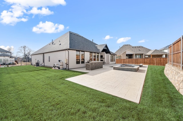 back of property with an outdoor hot tub, a yard, and a patio