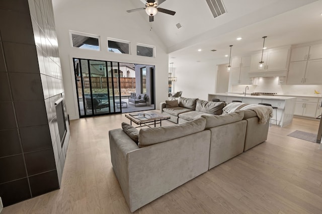 living room with light hardwood / wood-style flooring, high vaulted ceiling, and ceiling fan