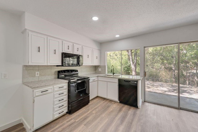 kitchen featuring light wood-type flooring, white cabinets, sink, and black appliances