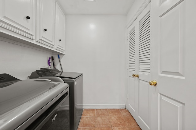 washroom with cabinet space, baseboards, washer and dryer, and light tile patterned flooring