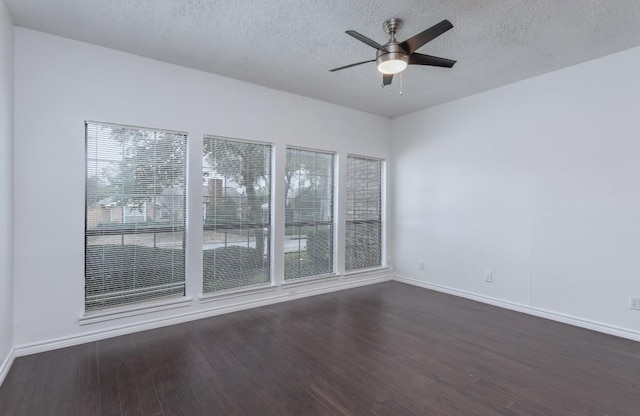 empty room featuring dark wood-type flooring, plenty of natural light, a textured ceiling, and ceiling fan