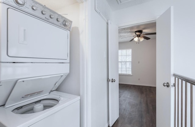 laundry area featuring stacked washer / drying machine, dark wood-type flooring, and a textured ceiling