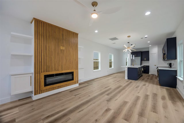 unfurnished living room with sink, ceiling fan, and light wood-type flooring