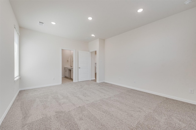 unfurnished bedroom with ensuite bath and light colored carpet