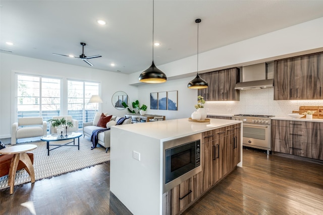 kitchen with high end stove, built in microwave, modern cabinets, wall chimney exhaust hood, and dark wood finished floors