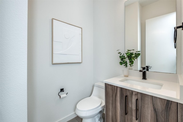 bathroom with toilet, baseboards, and vanity