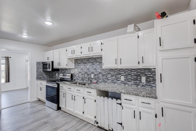 kitchen featuring white cabinetry, tasteful backsplash, light stone countertops, and appliances with stainless steel finishes