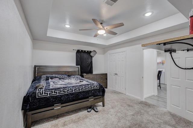 carpeted bedroom featuring washer / clothes dryer, ceiling fan, and a tray ceiling