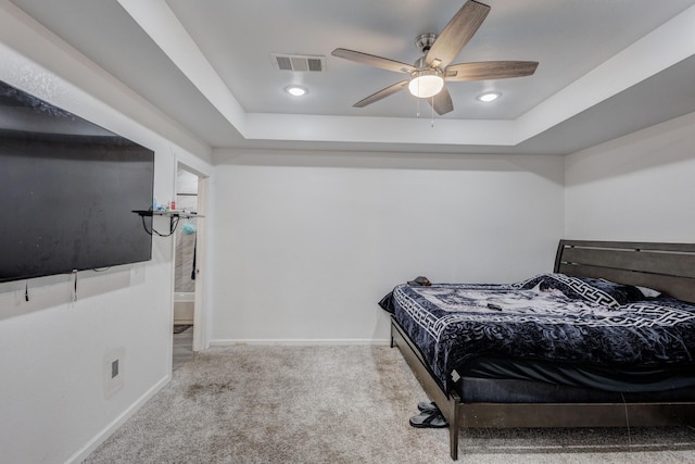 carpeted bedroom with a raised ceiling and ceiling fan