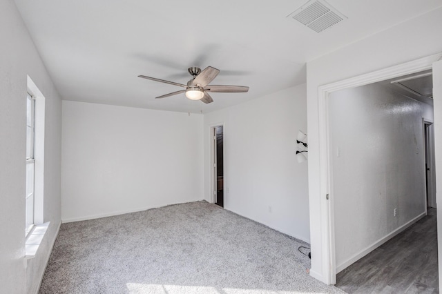 empty room with ceiling fan and dark colored carpet