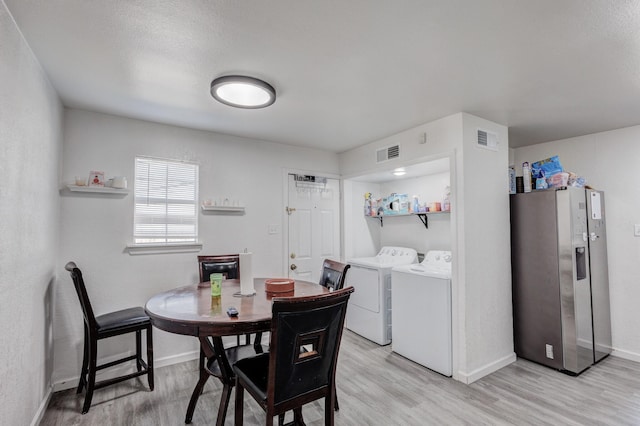 dining space featuring washing machine and dryer and light hardwood / wood-style floors