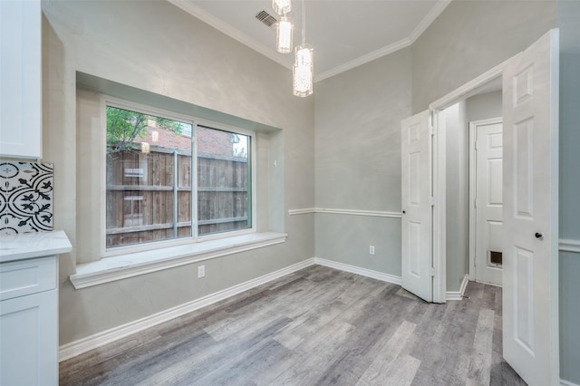 unfurnished dining area with ornamental molding and light hardwood / wood-style floors