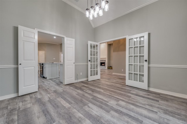 unfurnished room featuring french doors, high vaulted ceiling, crown molding, and light hardwood / wood-style floors