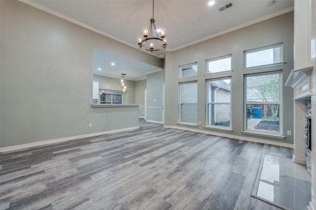 unfurnished living room featuring ornamental molding, a fireplace, light hardwood / wood-style flooring, and a notable chandelier