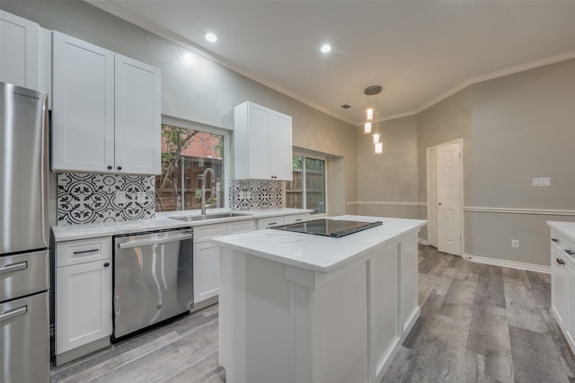 kitchen with sink, appliances with stainless steel finishes, white cabinetry, a center island, and decorative light fixtures